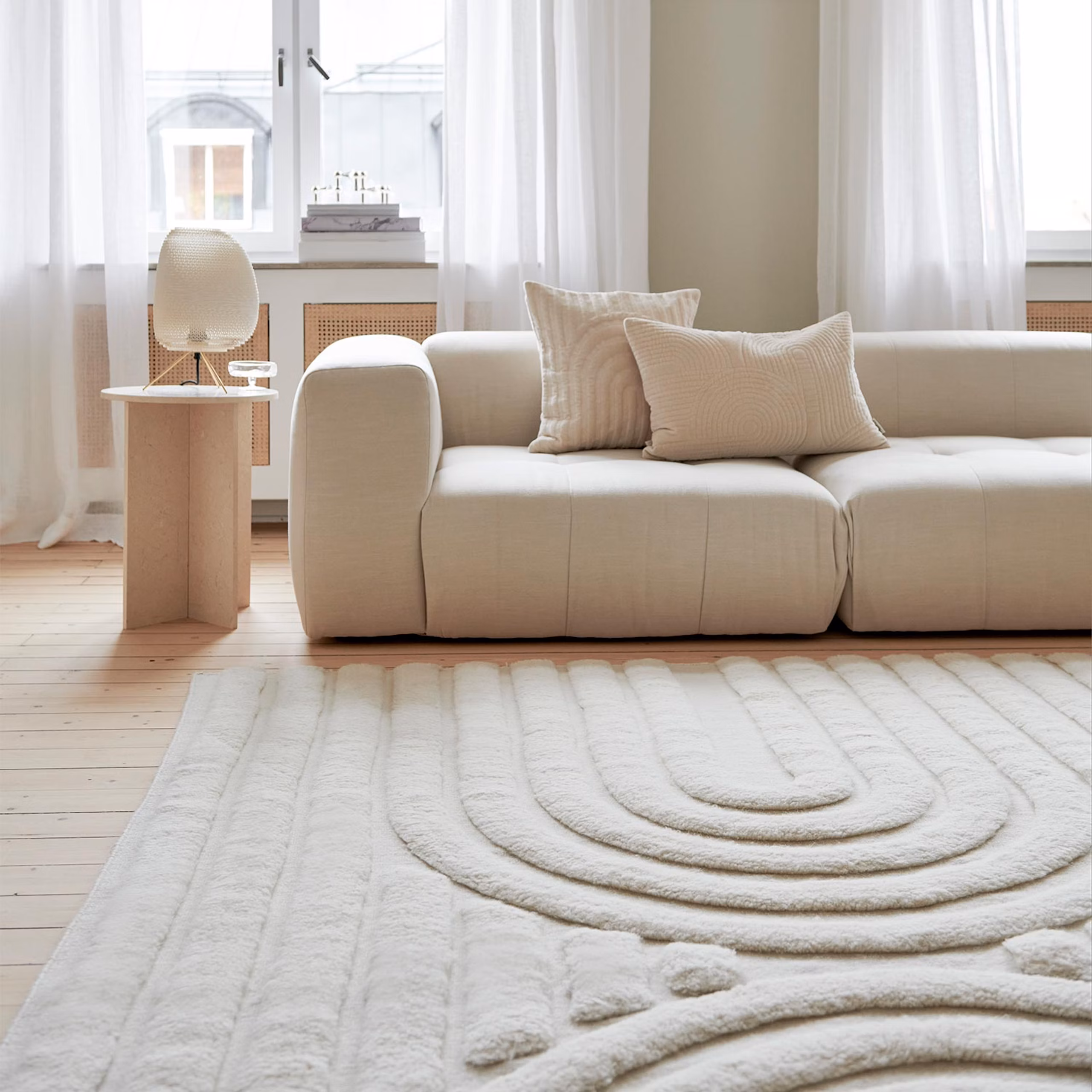 HemstÃ¤dning Stockholm - Ljust vardagsrum med beige soffa och vit matta pÃ¥ trÃ¤golv